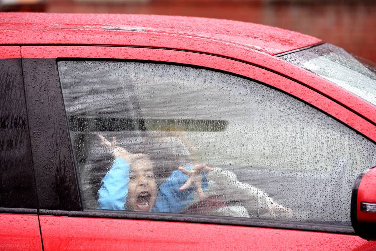 Luca Scott, 5, of Williamstown, Vt., makes faces at his parents through the window of a car parked next to their barbecue stand as they set up in Chelsea, Vt., on Friday, April 12, 2024. His parents have just started Scott Family BBQ and they use local pork for their pulled pork and baby back ribs. Luca's mother was about to take him to school for picture day. (Valley News - Jennifer Hauck) Copyright Valley News. May not be reprinted or used online without permission. Send requests to permission@vnews.com.