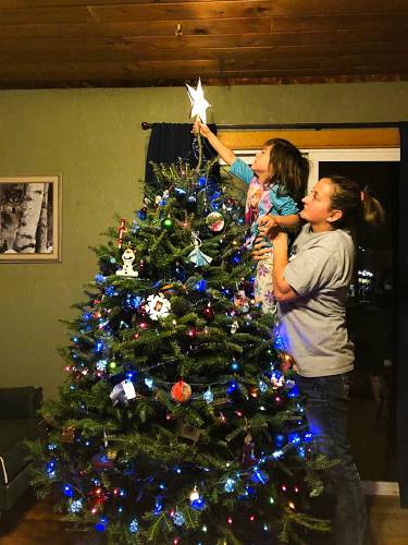 Christina Chatlos lifts her daughter Hailey, 3, to put the star on their Christmas tree in Williamstown, Vt., around 2016.  Photo courtesy of Thomas Ferranti