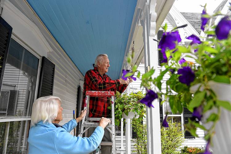 Chuck and Alean Hunnewell hang plants along their porch in Lebanon, N.H., on Monday, May 13, 2019. The plants-- a petunia and fuschia--were Mother's Day gifts from their children and grandchildren. (Valley News - Jennifer Hauck) Copyright Valley News. May not be reprinted or used online without permission. Send requests to permission@vnews.com.