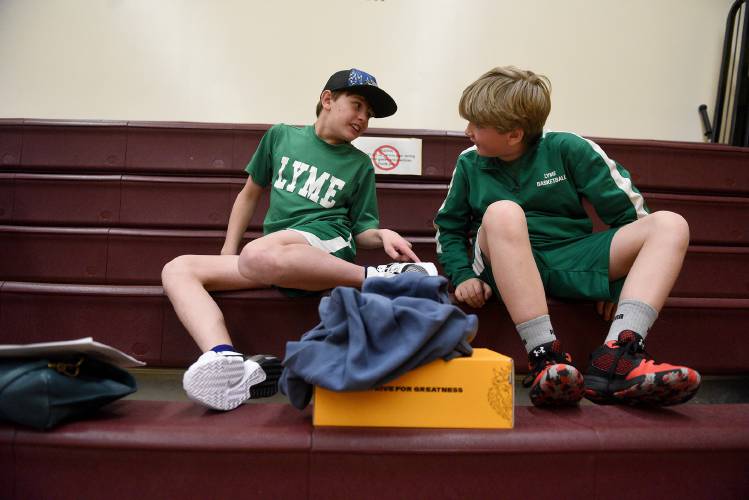 Before the start of their game, Lyme players Joe Simpson, left, and Jack Thompson watch from the bleachers during the Karp’s Klassic on Thursday, March 14, 2024, in Lebanon, N.H. Simpson had just put on his new pair of sneakers for their game. (Valley News - Jennifer Hauck) Copyright Valley News. May not be reprinted or used online without permission. Send requests to permission@vnews.com.