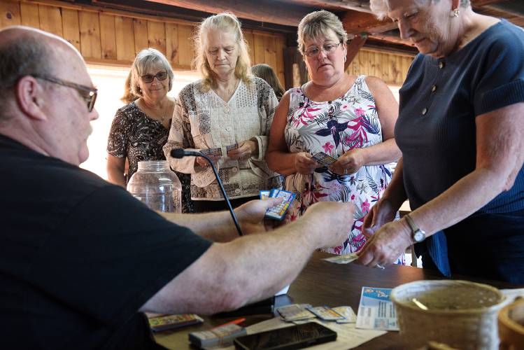 Bingo caller Roy Holland, of Enfield, sells Long Shot pull tickets to, from left, Sue Rocke, of Canaan, Sandy Benjamin, of Enfield, Deb Wilbur, of Plainfield, and Mary Jane Thibodeau, of West Lebanon, before the main bingo game at the LaSalette Shrine in Enfield, N.H., on Tuesday, August 1, 2023. The grey hound themed game is played between bingo games and uses the bingo balls to draw numbers that match a winning card for a guaranteed payout. (Valley News - James M. Patterson) Copyright Valley News. May not be reprinted or used online without permission. Send requests to permission@vnews.com.