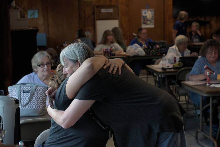 Vicki Pellerin, of Enfield, right, gets a hug from Tammie Decato Hughes, of Enfield, during the weekly Bingo night at the LaSalette Shrine in Enfield, N.H., on Tuesday, August 1, 2023. (Valley News - James M. Patterson) Copyright Valley News. May not be reprinted or used online without permission. Send requests to permission@vnews.com.