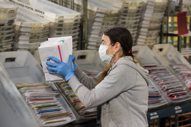 Carol Fairbanks loads sorted mail into bins at the U.S. Postal Service processing plant in White River Junction, Vt., Tuesday, April 14, 2020. (Valley News - James M. Patterson) Copyright Valley News. May not be reprinted or used online without permission. Send requests to permission@vnews.com.
