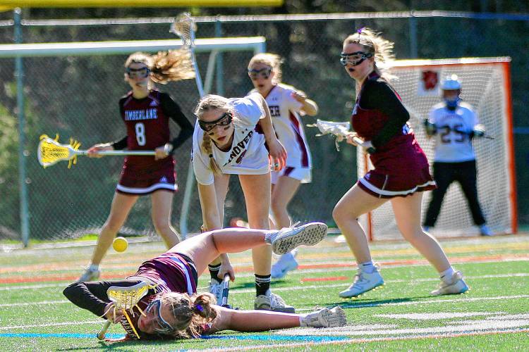 Timberlane High's Maia Parker crashes onto the turf at Merriman-Branch Field, watched by Hanover's Eleanor Edson during the NHIAA Division II teams' April 25, 2024, game in Hanover, N.H. Hanover won, 13-5. (Valley News - Tris Wykes) Copyright Valley News. May not be reprinted or used online without permission. Send requests to permission@vnews.com.