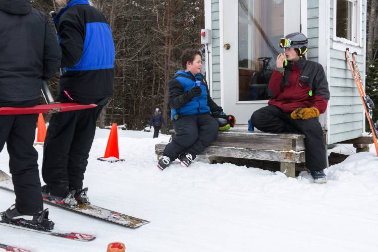 Jacob McCrillis, 18, right, communicates with another volunteer at the base of the hill while operating the t-bar at Northeast Slopes in East Corinth, Vt., on Wednesday, Jan. 31, 2024. Teegan Gilmore, 12, left, of Newbury, takes a break to watch McCrillis at his work. Gilmore said he skis at Northeast Slopes, where lift tickets are $15 a day, because, “It’s cheap and it’s near where I live.” (Valley News - James M. Patterson) Copyright Valley News. May not be reprinted or used online without permission. Send requests to permission@vnews.com.
