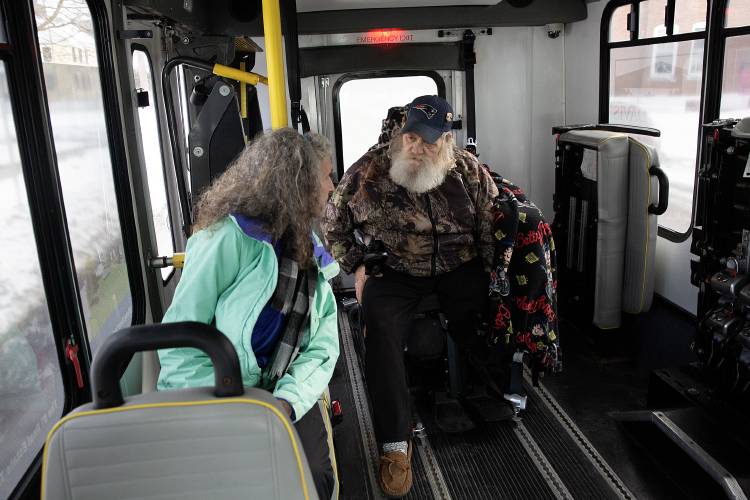 Thomas Reynolds, right, talks to his home health aide Nylene Robinson after being picked up from his home for a doctor’s appointment by the MOOver microtransit bus in Windsor, Vt., on Tuesday, Jan. 31, 2023. The pair don’t have another form of transportation and would typically make the 25-minute trek to Mt. Ascutney Hospital with Robinson walking next to Reynolds in his wheelchair. “Every time I’ve called they’ve been right there,” Reynolds said of MOOver. (Valley News / Report For America - Alex Driehaus) Copyright Valley News. May not be reprinted or used online without permission. Send requests to permission@vnews.com.