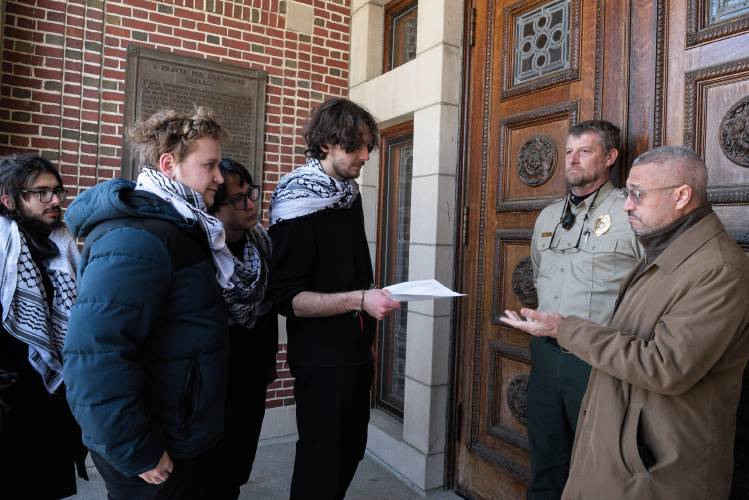 Palestinian-American student Ramsey Alsheikh, center, hands over a list of demands to Dartmouth College's Director of Safety and Security Keysi Montas, right, at the entrance of Parkhurst Hall in Hanover, N.H., during a rally to announce that he and seven classmates are initiating a hunger strike on Monday, Feb. 19, 2024. They requested the demands, which include dropping charges against two students who were arrested during a protest last October, and divesting from investments that support Israeli-Palestinian apartheid, and recognizing and protecting Palestinian students on campus. From left are hunger-stirkers Jordan Narrol, Calvin George and Paul Yang. Sgt. Greg Timmins, of Dartmouth Safety and Security, is second from right. (Valley News - James M. Patterson) Copyright Valley News. May not be reprinted or used online without permission. Send requests to permission@vnews.com.