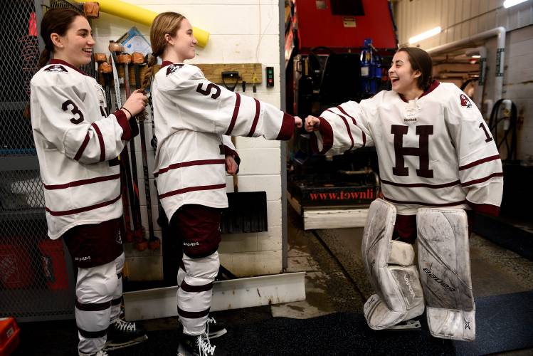 Lucy Braga gives Hanover hockey goalie J.J. Masland a fist bump while teammate Hannah Gardner braids her hair before the start of their game with Bishop Guertin on Saturday, Feb. 17, 2024. Hanover won, 6-0.  (Valley News - Jennifer Hauck) Copyright Valley News. May not be reprinted or used online without permission. Send requests to permission@vnews.com.