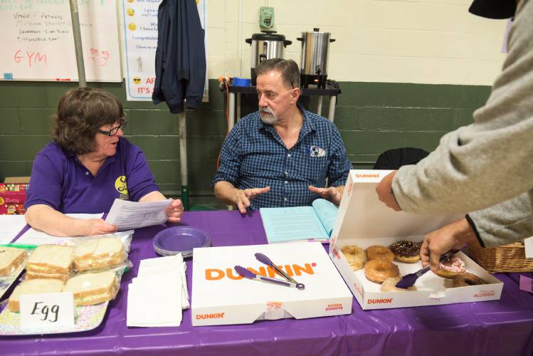 Sharon Phinney, left, and Jay Adams discuss the town warrant while staffing the Enfield Mascoma Lioness Club snack table before the start of Enfield, N.H., Town Meeting on Saturday, March 16, 2024. They offered coffee, donuts, sandwiches and chips by donation. (Valley News - James M. Patterson) Copyright Valley News. May not be reprinted or used online without permission. Send requests to permission@vnews.com.