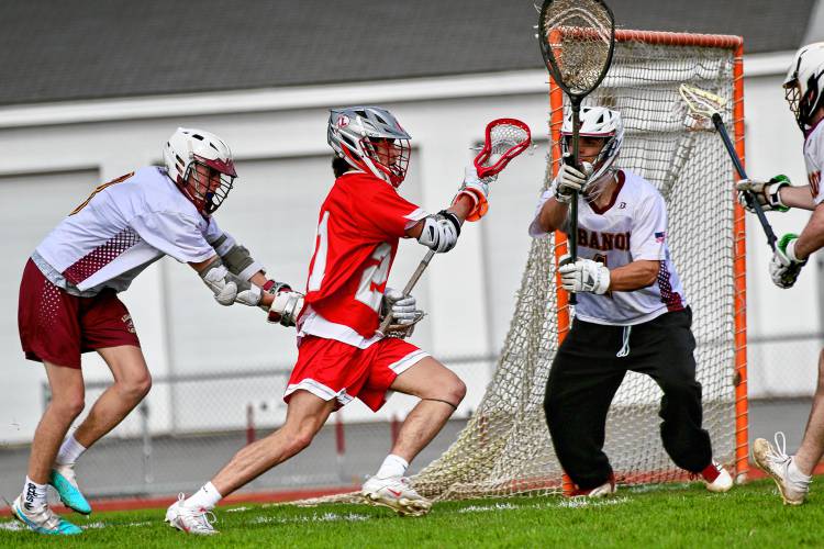Laconia High's Eli Nadeau, center, turns the corner on Lebanon's Austin Engert, left, while goaltender James Barnett prepares for a shot during the NHIAA Division III teams' April 17, 2024, meeting on Henry Emerton Field in Lebanon, N.H. Laconia won, 8-2. (Valley News - Tris Wykes) Copyright Valley News. May not be reprinted or used online without permission. Send requests to permission@vnews.com. 