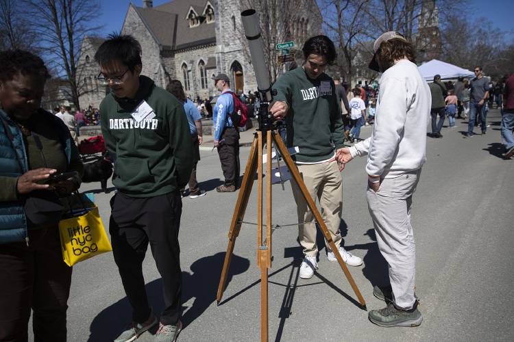 Dartmouth Physics and Astronomy Department PhD students Martin Ying, center left, and George Dufresne, center right, teach attendees about the total solar eclipse outside of the Fairbanks Museum and Planetarium in St. Johnsbury, Vt., on Monday, April 8, 2024. (Valley News / Report For America - Alex Driehaus) Copyright Valley News. May not be reprinted or used online without permission. Send requests to permission@vnews.com.