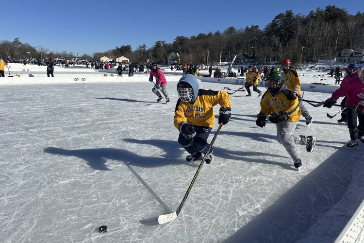 Hockey players go for the puck during the final of the women's open division at the Pond Hockey Classic in Meredith, N.H., on Sunday, Feb. 4, 2024. Like many winter traditions on lakes across the U.S., pond hockey is under threat from climate change. (AP Photo/Nick Perry)
