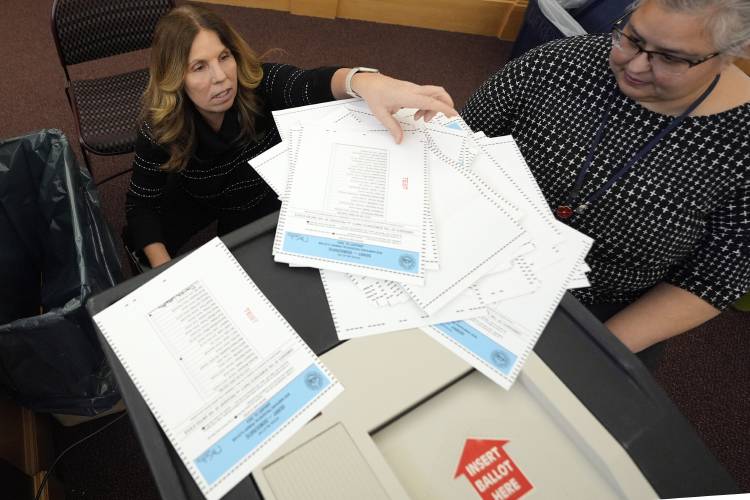 File - Lynne Gagnon, Derry, N.H. deputy town clerk, left, unloads test ballots from a storage cart as Tina Guilford, Derry town clerk, prepares to load them into the ballot counting machine again while testing the machines ahead of the New Hampshire primary, at the Derry Municipal Center, Tuesday, Jan. 16, 2024. (AP Photo/Charles Krupa, File)