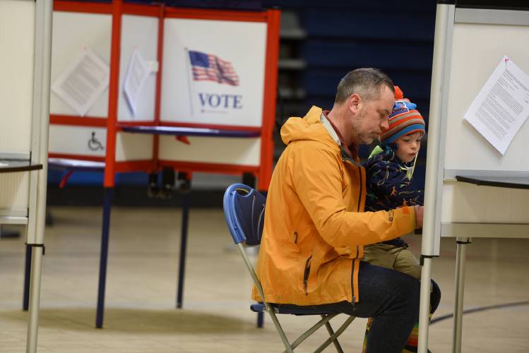 Hartford voter Mike Goudzwaard sits with his son Sam, 3, when voting on the Hartford school budget and bond on Monday, April 15, 2024, in White River Junction, Vt. Goudzwaard said Sam had given him some advice on how to vote. 