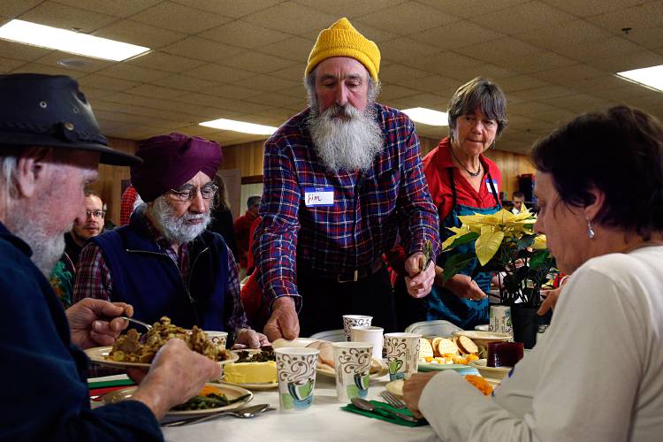 Jim and Sue Fitch, of Cornish, N.H., serve, from left, Philip Allan, of Piermont, N.H., Harjit Rakhra, Norwich, Vt., and Sandy James, of Newbury, Vt., at the annual Lebanon Christmas Day Dinner in Lebanon, N.H., on Dec. 25, 2018. The diners said they have been coming for several years and return to meet new people. (Valley News - Geoff Hansen) Copyright Valley News. May not be reprinted or used online without permission. Send requests to permission@vnews.com.