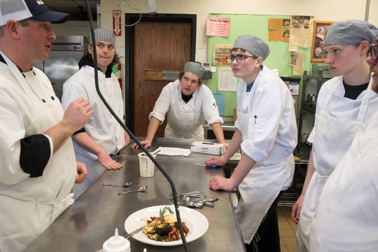 Chef Patrick Gobeille, left, critiques a dish cooked during a practice session for Junior Iron Chef Vermont by Hartford Area Career and Technology Center culinary students, from back left, Gianni Hossler, 16, Brayden Bennett, 16, Andrew Singleton, 16, Greyson Renninger, 17, and Brandon Driver, 17, in White River Junction, Vt., on Friday, March 1, 2024. On Saturday, March 9, students from the program will travel to the Champlain Valley Exposition in Essex Junction, Vt., for the competition where they will have 90 minutes to prepare their predetermined recipe - a ricotta stuffed portabella mushroom with Roma tomatoes and asparagus on top of maple polenta with balsamic marinade. (Valley News - James M. Patterson) Copyright Valley News. May not be reprinted or used online without permission. Send requests to permission@vnews.com.