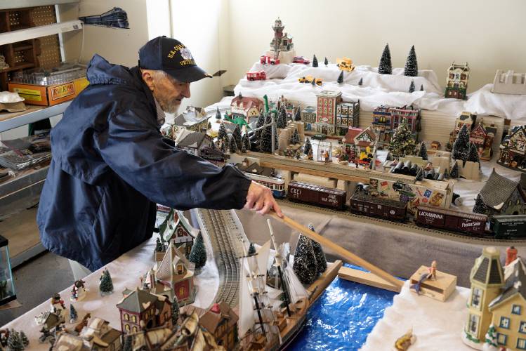 When Bob Stange, 84, learned that the home he and his wife have rented in White River Junction, Vt., for the last 16 years was under contract to be sold, he knew he would have to give up his train set, which takes up a corner of the garage beneath the apartment. Because of the kindness shown him by members of St. Paul's Episcopal Church, he decided to raffle the set in an effort to raise $1,000 for its People's Needs Fund. Twenty tickets for the raffle are available for $50 each at the Upper Valley Food Co-op, where Stange cleans the floors six nights a week. Because of his work, Stange does not qualify for subsidized housing and is looking for a market rate apartment to rent in the Upper Valley. Stange reaches to arranges a model that is part of his layout in his White River Junction, Vt., garage on Friday, Dec. 1, 2023. (Valley News - James M. Patterson) Copyright Valley News. May not be reprinted or used online without permission. Send requests to permission@vnews.com.
