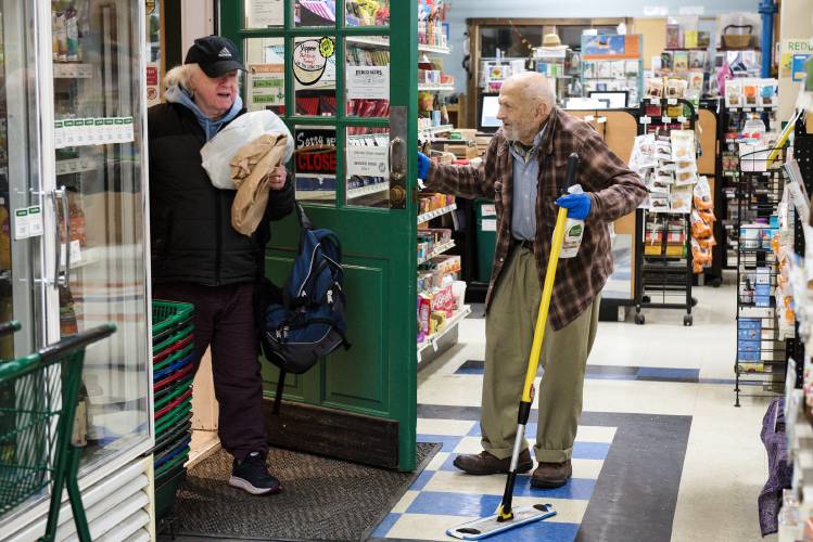 Bob Stange, 84, of White River Junction, opens the door for produce manager Robert Lucas as he arrives for work at the Upper Valley Co-op on Wednesday morning, Dec. 6, 2023. Stange has continued to work even while facing cancer. “Every time he’s got to go to the hospital, you say, oh, no, no. But he bounces back.” said Lucas. “I don’t know where the strength comes from, but he’s got a lot of it.” (Valley News - James M. Patterson) Copyright Valley News. May not be reprinted or used online without permission. Send requests to permission@vnews.com.