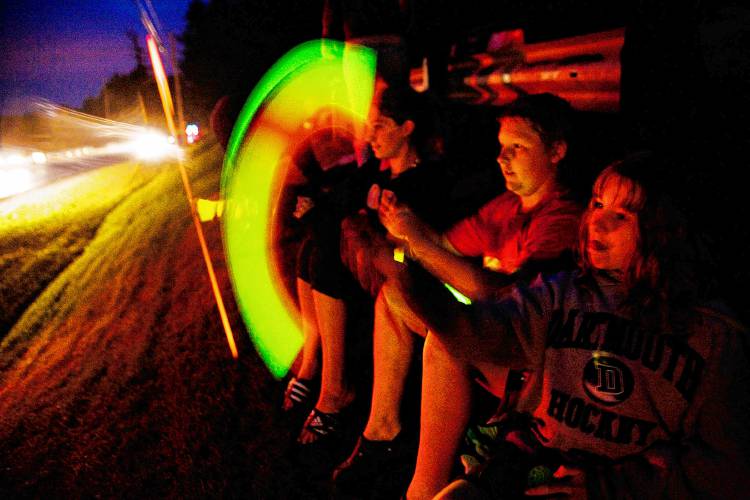 From right, Alicen Sanville, 9, of West Lebanon, N.H., her brother and sister, Mike Sanville, 12, and Brittany Hathorn, 14, wave glow lights while they wait for the beginning of fireworks by Route 10 and the Connecticut River in West Lebanon, N.H., on July 4, 2007. (Valley News - Ikuru Kuwajima) Copyright Valley News. May not be reprinted or used online without permission. Send requests to permission@vnews.com.