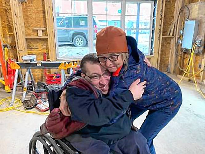 C.J. Lanzim is hugged by Sylvia Kluge Dow, executive director of Visions for Creative Housing Solutions, while visiting his future apartment. (Family photograph)