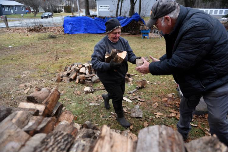 Carol and Ken Hooker, of Canaan, N.H., have worked together in their lawn care business for 35 years -- on Wednesday, Jan. 3, 2024, they stack firewood at a client's home in Lebanon, N.H. The pieces of wood needed to be cut in half with a chainsaw because the homeowners bought a smaller stove and the wood was too large. The Hookers were married on Valentine's Day 47 years ago. 
