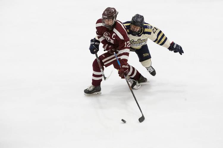 Hanover forward Jack Wilkinson (12) moves the puck down the ice while Windham defenseman Joseph Gilbert (21) reaches around him with his stick during the NHIAA D-I boys hockey semifinal game at JFK Memorial Coliseum in Manchester, N.H., on Wednesday, March 6, 2024. (Valley News / Report For America - Alex Driehaus) Copyright Valley News. May not be reprinted or used online without permission. Send requests to permission@vnews.com.