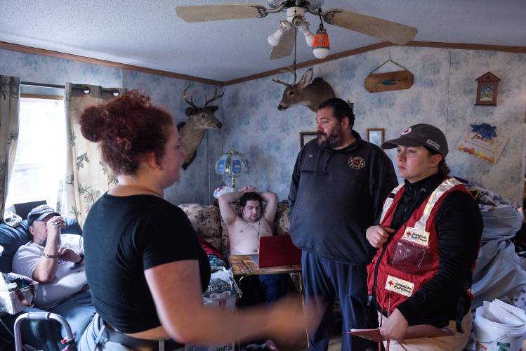 Since their father James LaCount I was killed in a house fire in July, Micheala LaCount, 21, her brother James LaCount II, 23, center, and their mother Gwen LaCount, not pictured, moved in with Gwen's brother Matt Rice, left, and their parents only steps away from their destroyed trailer home. Lydnsey Morin, Red Cross disaster program manager for Southern Vermont, right, and Corinth Volunteer Firefighter Tim Wilder, second from right, visited the family to install new smoke detectors in the trailer in West Newbury, Vt., as part of a one-day mini-installation for the Red Cross's home fire campaign on Saturday, Oct. 21, 2023. (Valley News - James M. Patterson) Copyright Valley News. May not be reprinted or used online without permission. Send requests to permission@vnews.com.