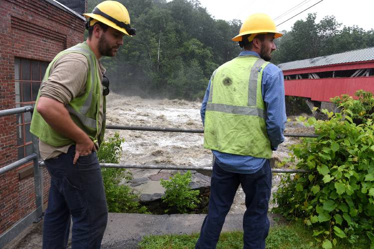 Chance Lister, left, and Parker Cutting, of Green Mountain Power, checked the substation in Taftsville, Vt., after heavy rains caused flooding throughout the Twin States on Monday, July 10, 2023. The Ottauquechee River was running high and fast near the substation. (Valley News - Jennifer Hauck) Copyright Valley News. May not be reprinted or used online without permission. Send requests to permission@vnews.com.