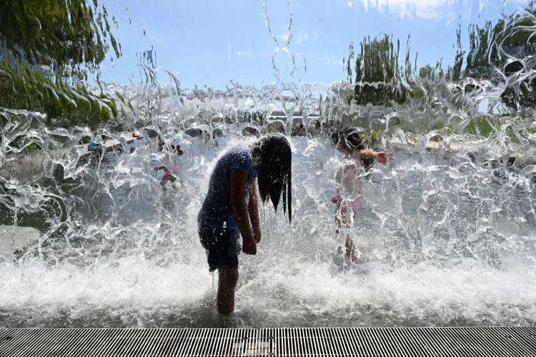 A child cools off in a waterfall feature at the Yards Park on Monday in Washington as temperatures soared into the upper 90s. MUST CREDIT: Washington Post photo by Matt McClain