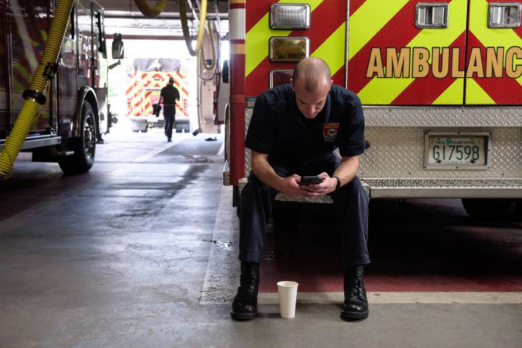 Lebanon Firefighter and EMT Corey Bartlett checks his messages on the apparatus floor at Station 1 in Lebanon, N.H., on Wednesday, Sept. 29, 2023. The station’s aging Plymovent system, which captures exhaust from the trucks in a series of yellow tubes and vents it to the outside, is nearing its “end of life,” and cannot fully prevent staff from exposure said Capt. Chris Buchanan. (Valley News - James M. Patterson) Copyright Valley News. May not be reprinted or used online without permission. Send requests to permission@vnews.com.