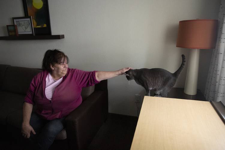 Rosemary, who asked to be referred to be her first name out of concerns for her safety, pets her five-year-old cat Twister in her room at the Residence Inn where she is living temporarily in Lebanon, N.H., on Monday, March 25, 2024. Rosemary, who is in the process of searching for permanent housing, has been at the hotel since March 8 after the apartment building in West Lebanon where she had been living for nearly nine years was condemned. The transition has been difficult, Rosemary said, but she has had a lot of help. “I know there’s something coming,” she said. (Valley News / Report For America - Alex Driehaus) Copyright Valley News. May not be reprinted or used online without permission. Send requests to permission@vnews.com.