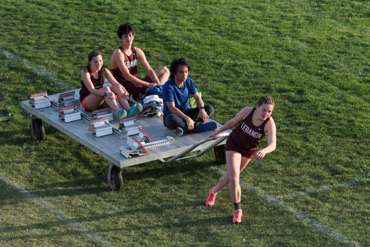 Rachel Horak, right, pulls her Lebanon teammates, from left, Grace D'Entremont, Daniel Calderon-Rios, and Ryle Isuga, while picking up blocks and hurdles around the track after the 300 meter hurdles races during a meet with Hanover, Thetford, Hartford, Newport, Stevens and White River Valley in Lebanon, N.H., on Tuesday, April 24, 2024. (Valley News - James M. Patterson) Copyright Valley News. May not be reprinted or used online without permission. Send requests to permission@vnews.com.