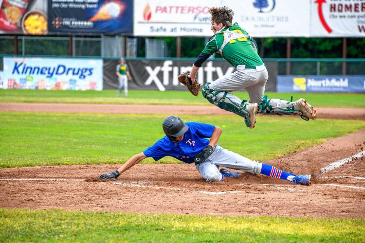 Thetford's Xander Oshoniyi slides safely into home over the leap of White River Valley catcher Brayden Russ during Saturday's D-III championship game at Centennial Field. (Tim Calabro / White River Valley Herald)