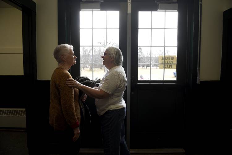 Friends Nancy Metz, left, and Derry Gleason, both of Newbury, Vt., take a moment to say hello during Newbury’s Town Meeting on Tuesday, March 5, 2024. Metz said she is proud of the community coming together for the tradition of Town Meeting, 