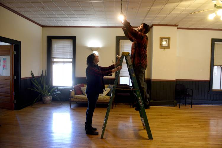 New owners of the Arnold Block building in Bethel, Vt., Chris and Amanda Helali, of Vershire, Vt. replace a light bulb on Tuesday,  Oct. 31, 2023. The room is used as a community meeting space.(Valley News - Jennifer Hauck) Copyright Valley News. May not be reprinted or used online without permission. Send requests to permission@vnews.com.