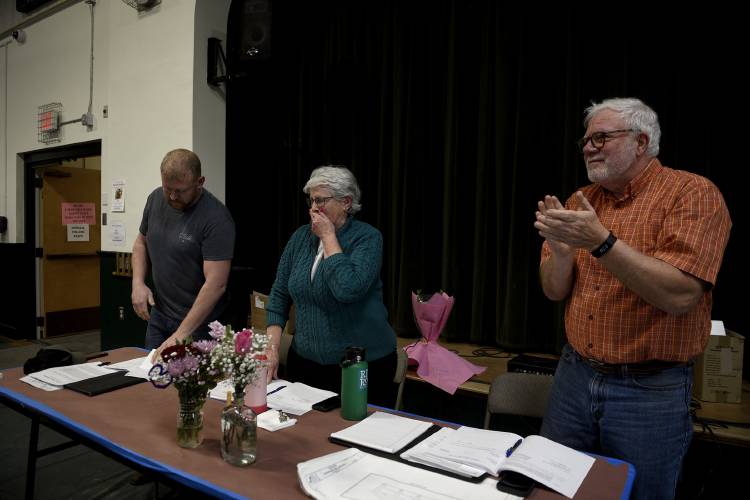 Along with others in attendance at Town Meeting, Newbury Selectboard members Joe Parsons, left, and Jeff McKelvey pay tribute to fellow board member Alma Roystan, middle, who has been on the selectboard for 27 consecutive years on Tuesday, March 5, 2024, in Newbury, Vt. Roystan is retiring from the board. 
 (Valley News - Jennifer Hauck) Copyright Valley News. May not be reprinted or used online without permission. Send requests to permission@vnews.com.