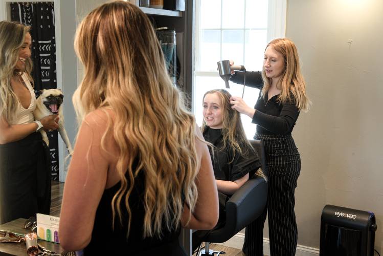Stylist Alexianna Merril, right, works on the hair of Dartmouth junior Stephanie Sowa, of Las Angeles, at Maven salon in Hanover, N.H., on Friday, July 28, 2023, as owner Kayla Brannen, holding the shop dog Dude at left, talks with another customer and stylist Jasmine Bender, middle. Brannen, who has worked as a stylist at the salon for 20 years,  bought the business in 2017 and is now preparing to move into a remodeled space on the building’s ground floor end of August. Brannen employs 15 stylists and said the move will improve accessibility, invite walk-in customers, and contribute to a more vibrant atmosphere downtown. (Valley News - James M. Patterson) Copyright Valley News. May not be reprinted or used online without permission. Send requests to permission@vnews.com.