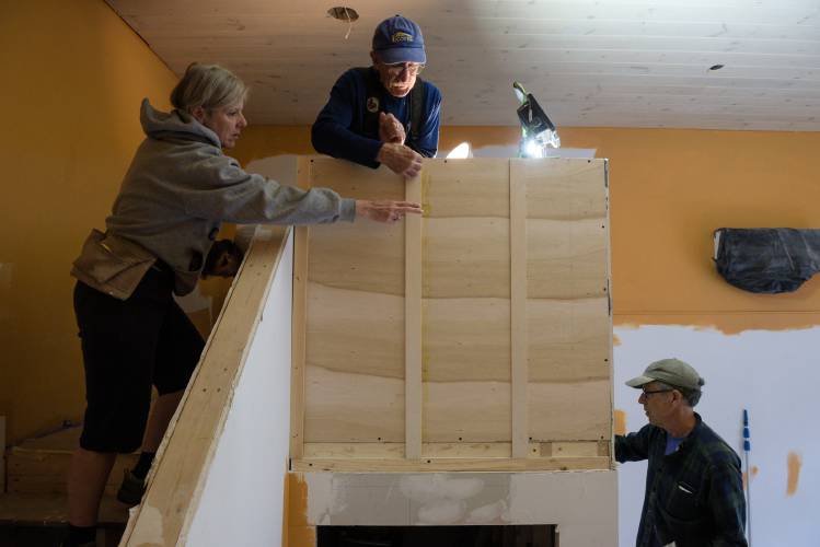 Volunteers Maria Markenson, of Quechee, left, and Hugh MacArthur, of Thetford, middle, prepare to mount drywall to the back of a book shelf as Habitat for Humanity project manager John Heath, of White River Junction, right, muds a wall in the space that will become Cover Home Repair’s book store in White River Junction, Vt., on Friday, Sept. 29, 2023. Cover will host a soft opening in the space as part of First Friday on October 6. Renovations undertaken to mark the organization’s 25th year also include an accessible, street-level office for home repair services. (Valley News - James M. Patterson) Copyright Valley News. May not be reprinted or used online without permission. Send requests to permission@vnews.com.