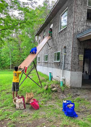 Bags of books are removed from Bruce MacPhail's outbuilding in Strafford, Vt., via a slide on Thursday, June 15, 2023. MacPhail was able to give away his 17,000 book collection in four days. (Courtesy Bruce MacPhail)