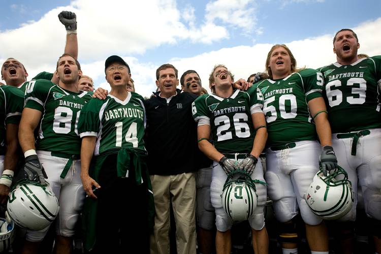 Dartmouth President Jim Yong Kim (14) and coach Buddy Teevens sing the school alma mater after yesterdayís win over Sacred Heart. 

Valley News - Geoff Hansen