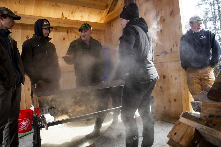 From left, seniors Seth Peters and Zak Guziewicz, school resource officer Matt Bunten, biology teacher Jennifer Fitzgerald and senior Aidan Smith boil sap in a sugar house built by Peters, Smith and their classmate Thomas Clifford at Mascoma Valley Regional High School in West Canaan, N.H., on Monday, March 18, 2024. Fitzgerald’s students started tapping sugar maples last year through a Tucker Mountain Challenge grant, and they hope to boil the 45 gallons of sap they’ve collected this year into about one gallon of syrup. (Valley News / Report For America - Alex Driehaus) Copyright Valley News. May not be reprinted or used online without permission. Send requests to permission@vnews.com.