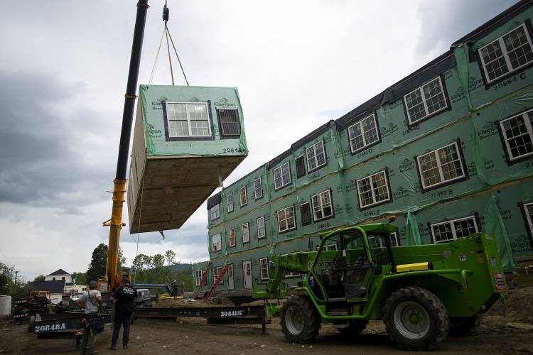 A construction crew assembles modular units manufactured by Ritz-Craft Corporation in Pennsylvania into a 42-unit workforce housing apartment building on Spring Street in Newport, N.H., on Thursday, June 15, 2023. Jack Franks, President and CEO of Avanru Development Group, filed a lawsuit in Superior Court against the town because of water and sewer connection fees, which he says are excessive and were not disclosed before the development began. (Valley News / Report For America - Alex Driehaus) Copyright Valley News. May not be reprinted or used online without permission. Send requests to permission@vnews.com.
