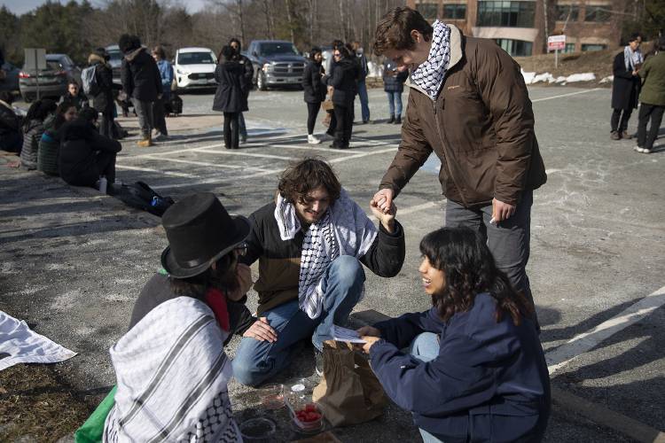 Dartmouth freshman Ben, top right, who declined to give his last name, shakes hands with sophomore Ramsey Alsheikh, center, president of the Palestine Solidarity Coalition, while he and junior Jordan Narrol, left, end their eight-day hunger strike during a protest outside of the Lebanon District Court in Lebanon, N.H., on Monday, Feb. 26, 2024. Alsheikh and Narrol were part of a group of eight students participating in the hunger strike, two of whom are continuing, and chose to break their fast with watermelon, a fruit that has been used as “a symbol of the Palestinian people,” Narrol said, because it bears the colors of the flag and grows in the region. (Valley News / Report For America - Alex Driehaus) Copyright Valley News. May not be reprinted or used online without permission. Send requests to permission@vnews.com.