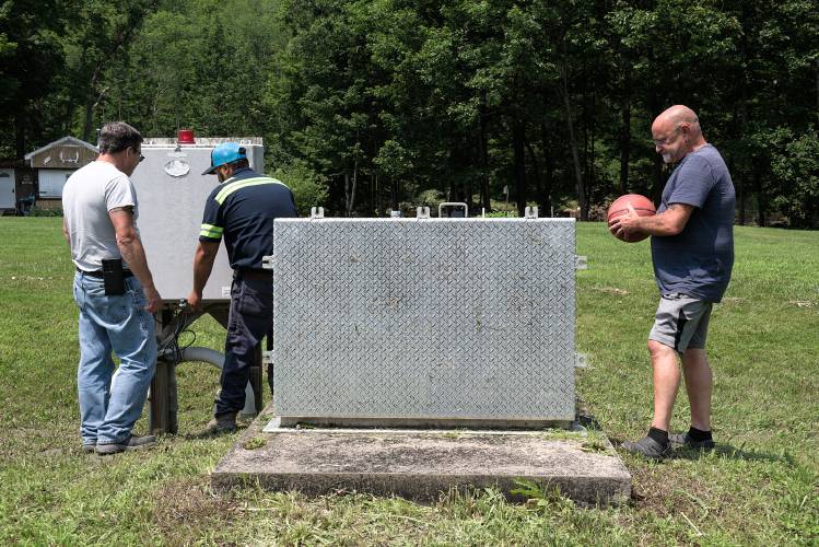Riverside Mobile Home Park resident Dana Brink, right, looks on as Tom Young, of the Vermont State Housing Authority, left, and Bill Dimmick, of Pump Tech, check the septic equipment before pumping out floodwater and silt on Tuesday, July 11, 2023. 