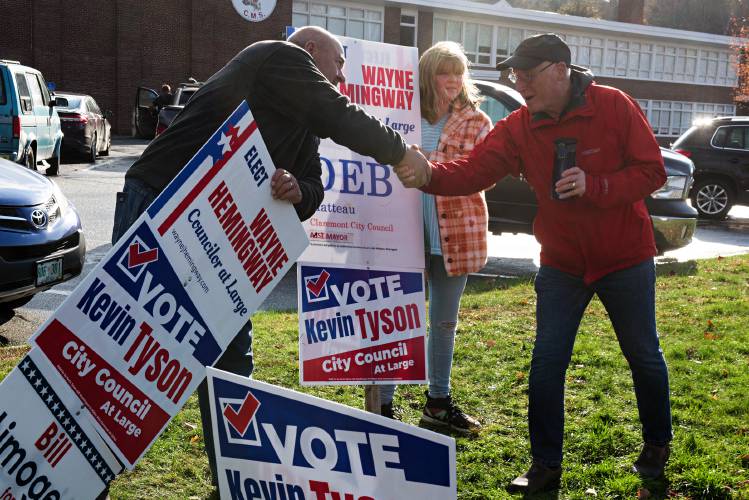 Mike Saracino, of Claremont, right, stops to greet councilor-at-large candidate Wayne Hemingway, left, as he campaigns with his daughter Emily Hemingway, 10, outside the polls at Claremont Middle School in Claremont, N.H., on Tuesday, Nov. 7, 2023. Saracino, a retired hospital pharmacist, campaigned for the 