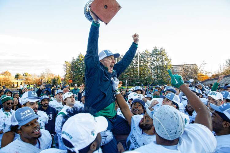 Dartmouth College football coach Sammy McCorkle holds the Ivy League championship trophy aloft during a celebration with the Big Green following its 38-13 win over Brown on Saturday in Providence, R.I. The Big Green’s win combined with Yale’s defeat of Harvard left all three schools with a share of the league title.