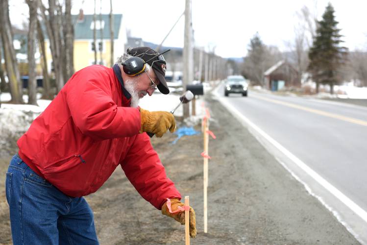 George Tessier, of Enfield, N.H., pounds posts along his lawn on Tuesday, Feb. 13, 2024. Tessier did not want people parking there. 