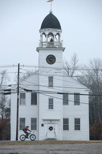 The Canaan Historical Society is seeking to raise more than $180,000 to repair rotting posts in the bell tower, sill timbers and windows in the town-owned 1793 Canaan Meetinghouse. A bicyclist passes the Meetinghouse on Canaan Street in Canaan, N.H., on Friday, Dec. 29, 2023. (Valley News - James M. Patterson) Copyright Valley News. May not be reprinted or used online without permission. Send requests to permission@vnews.com.