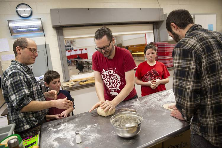 From left, Josh Mollov, Chip Mollov, 8, Christian Potter, all of Sharon, Vt., and Arhaea Lowe, 13, of South Royalton, Vt., take part in a pizza making class taught by Ryan Haac, of Sharon, during the first annual Sharon Skill Swap at Sharon Elementary School on Saturday, Feb. 10, 2024. “We don’t know each other anymore,” said Jen Donahue, who runs Sharon’s Old Home Days and was part of the team of volunteers that organized the skill swap. “We’re just trying to bring the community together more than once a year.” (Valley News / Report For America - Alex Driehaus) Copyright Valley News. May not be reprinted or used online without permission. Send requests to permission@vnews.com.