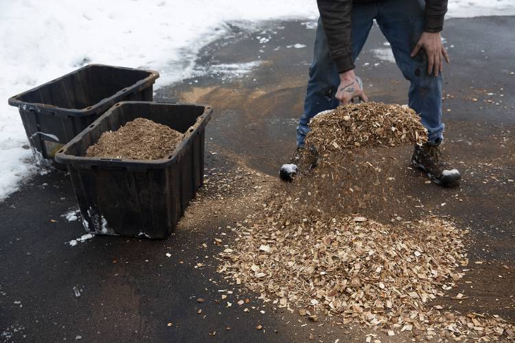 Lucas Perry, a truck driver for Froling Energy, cleans up wood chips that fell out of the truck during its drop off next to the Sherburne Gym in Sunapee, N.H., on Thursday, Feb. 1, 2024. The company sources wood chips from several area logging companies. “Why get rid of it when we can use it,” Perry said of the byproduct. (Valley News / Report For America - Alex Driehaus) Copyright Valley News. May not be reprinted or used online without permission. Send requests to permission@vnews.com.
